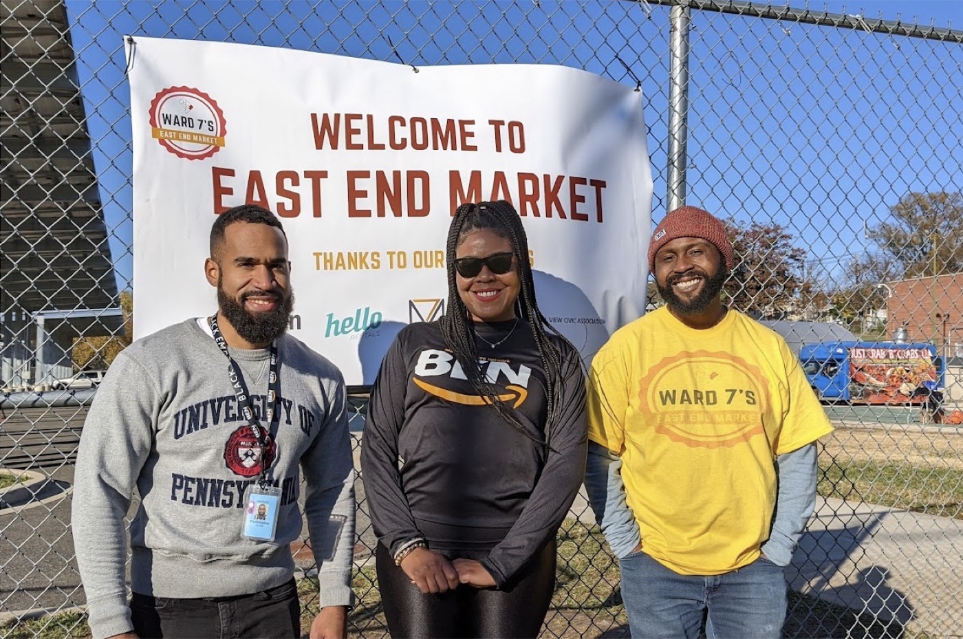 Three East End Market organizers standing in front of the market sign