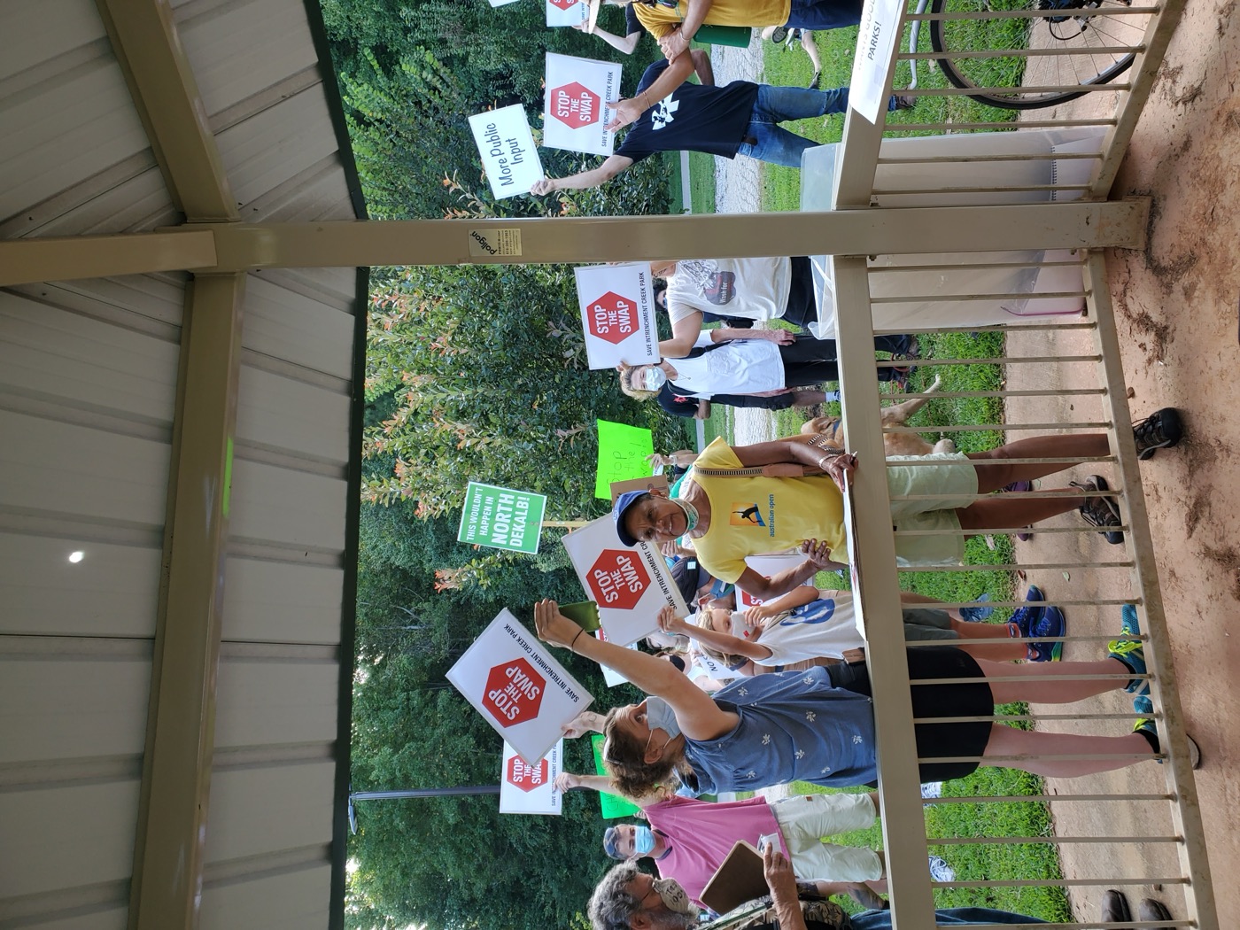 Neighbors holding signs during a public park advocacy meeting